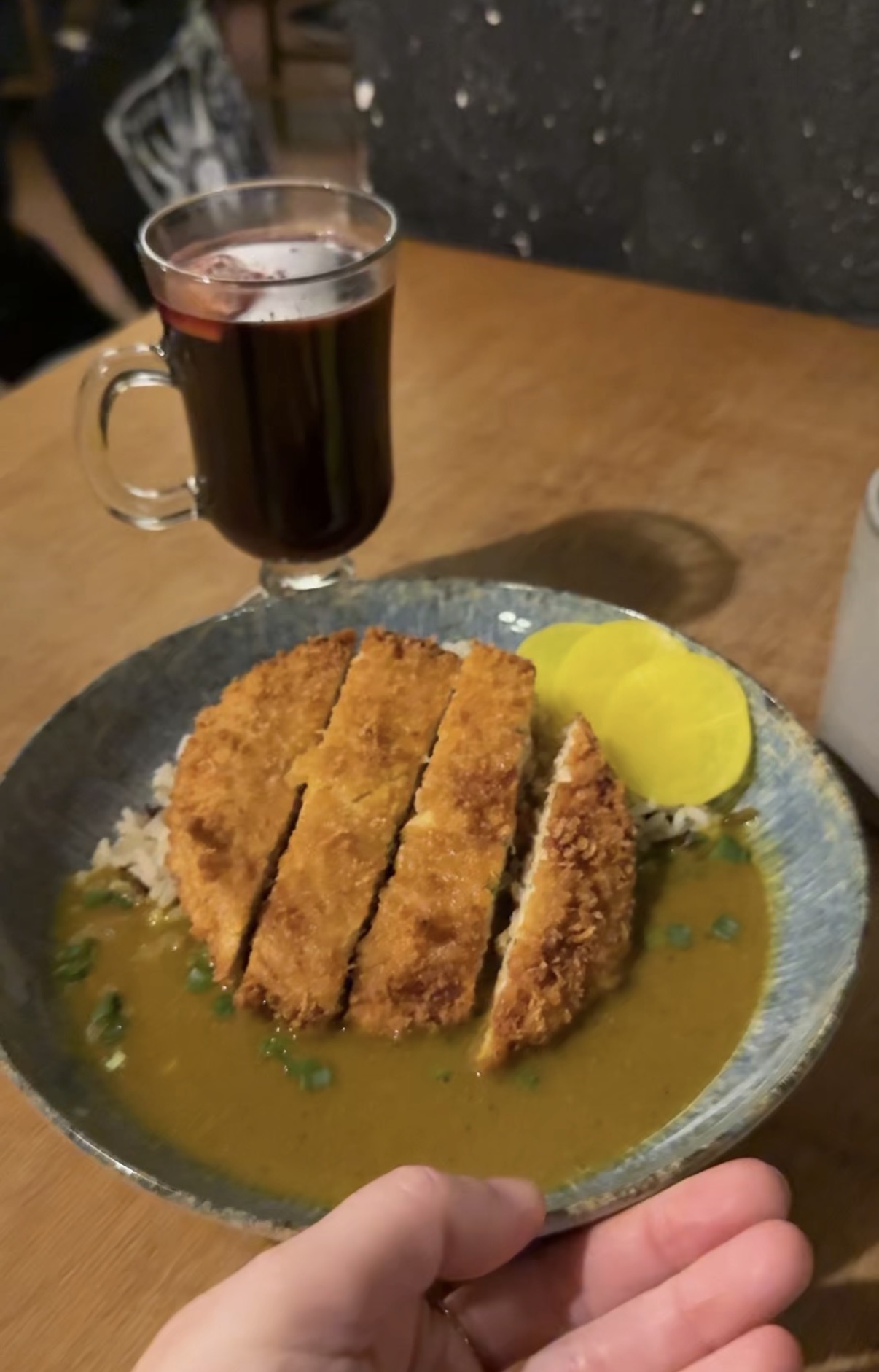 Vegan katsu curry with breaded cutlet, rice, pickles and mulled wine in Kraków