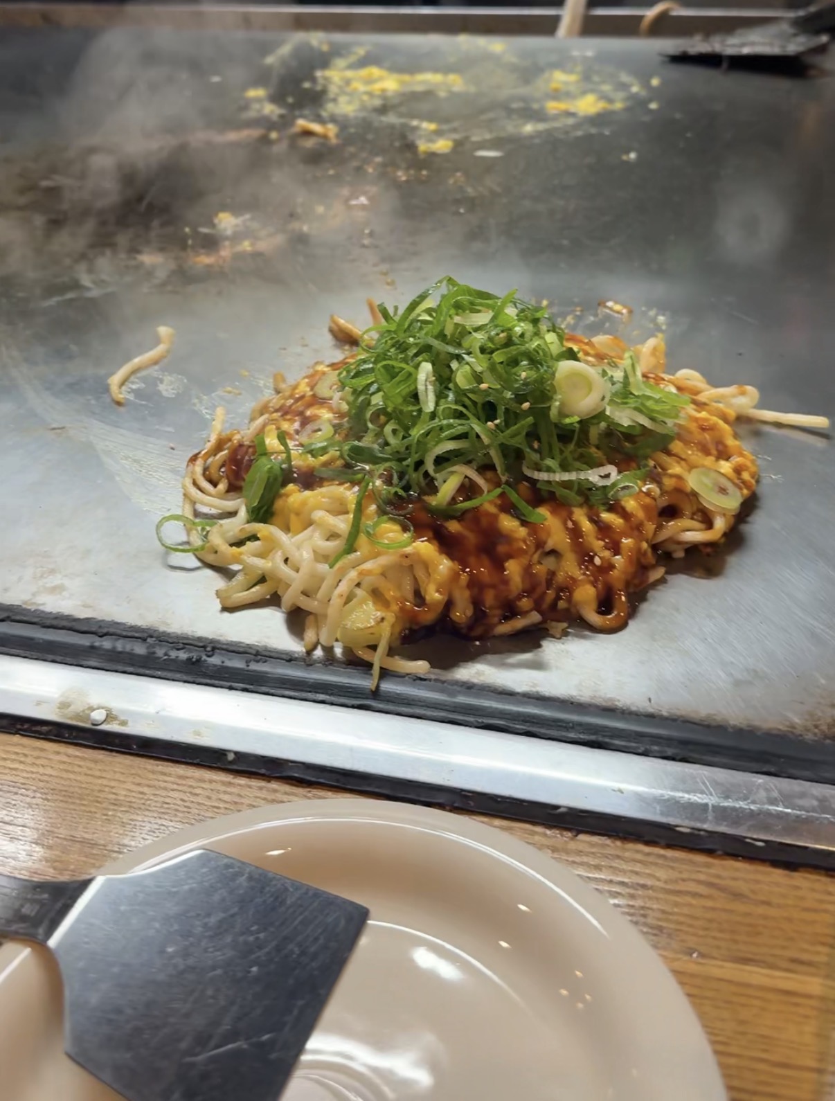 Hiroshima-style okonomiyaki topped with green onions on the teppan grill at Jirokichi