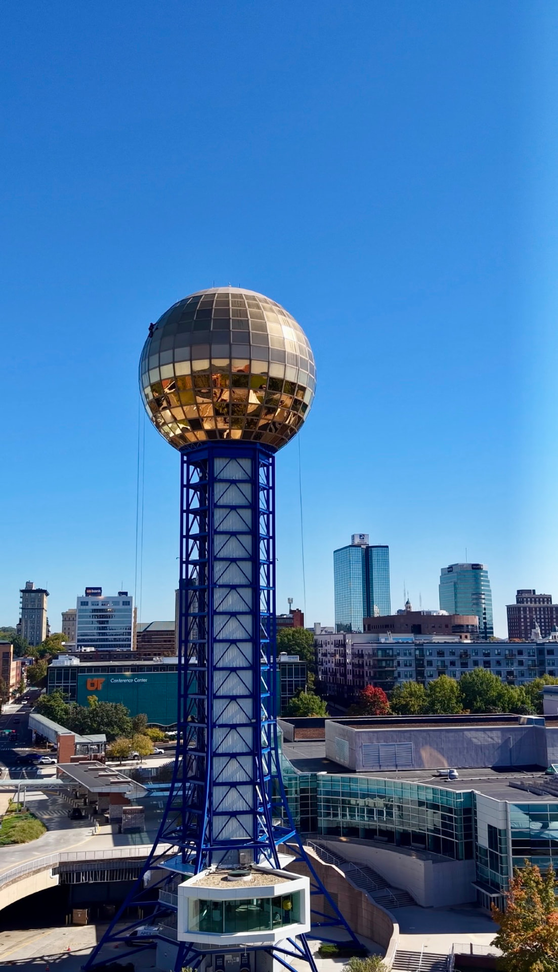 Aerial view of Knoxville’s golden Sunsphere on its blue steel tower with the downtown skyline under a clear blue sky